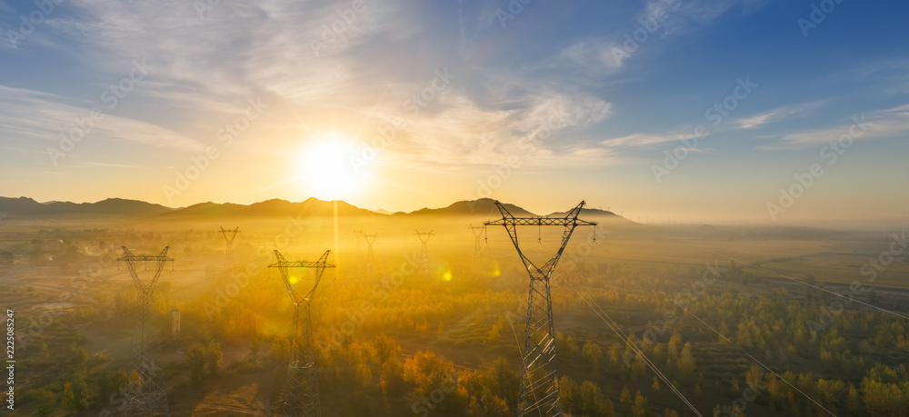 Naklejka premium High Voltage Transmission Pylons in Golden Morning Mist at Sunrise
