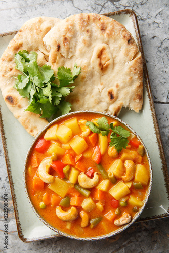 Vegetable korma is a rich and creamy Indian curry loaded with warm spices and tender veggies closeup on the bowl on the table. Vertical top view from above
