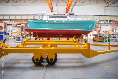 Bright turquoise boat rests on yellow transport frame