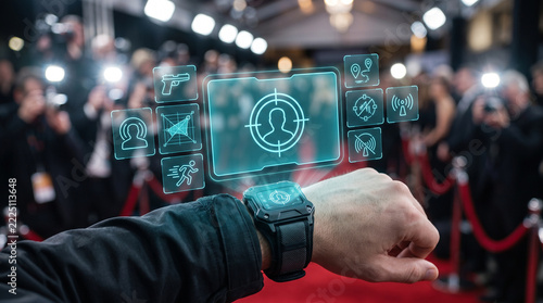Close-up of an elite bodyguard's wrist wearing a rugged smartwatch projecting a futuristic holographic security interface with target tracking and threat detection at a red carpet event