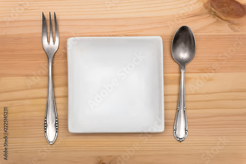Plate and spoon and fork on a wooden background