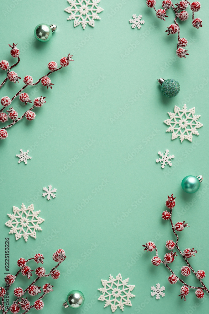 Naklejka premium Merry Christmas teal holiday vertical flat lay with snowflake ornaments, frosted berries and Happy New Year accents