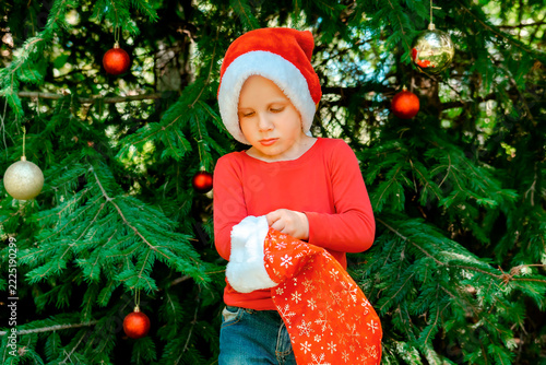 Child kid waiting for Christmas.little boy opening gift box near fir tree.winter festive holidays,family.Merry Christmas eve,New Year,Happy Holidays