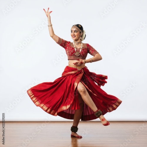 Young indian woman performing traditional classical dance in a colorful ethnic costume isolated on white background