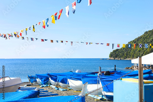 Riva Trigoso boats nautical flags Italy. Autumn coastal tranquility sea adventure mood. Mediterranean travel destination sailing guide.