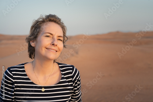 Happy mature woman in her fifties smiling in the desert with copy space