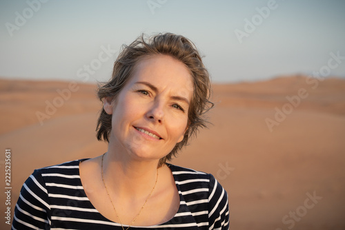 Confident woman in her fifties enjoying a peaceful moment in the desert at sunset