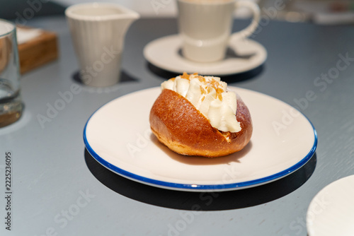 Sweet cream bun dessert with coffee cup on cafe table