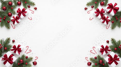 Christmas frame with gift boxes, red ornaments, and fir branches isolated on white background