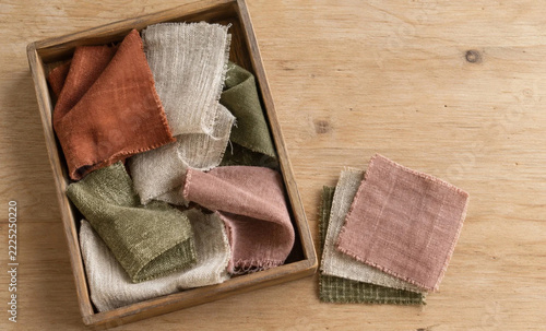Fabric scraps in a wooden tray beside stacked swatches