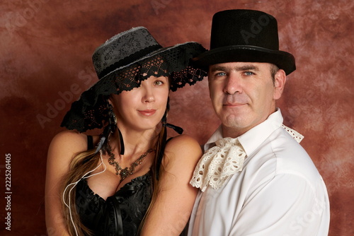 Vintage couple portrait in 19th-century Victorian attire and classic hats