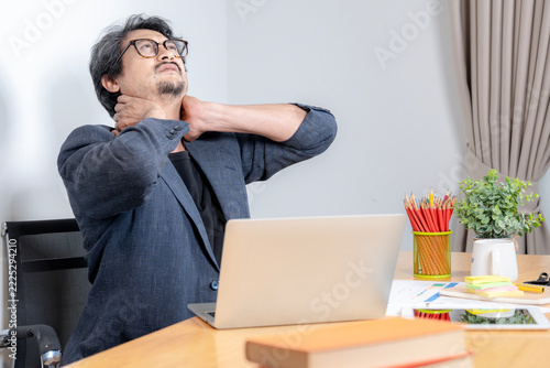 Businessman having neck ache and shoulder pain from working in the office