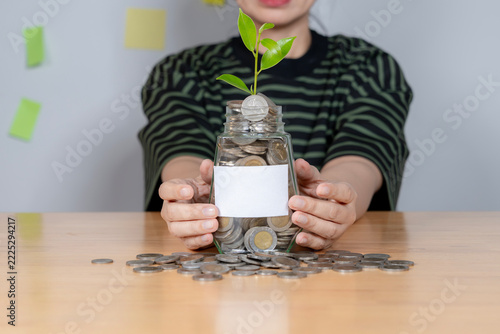 A close up shot of a woman hands covering a glass jar filled with coins to represent financial security and personal savings.