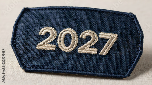 Dark blue fabric badge featuring detailed white embroidered digits representing the year two thousand twenty seven