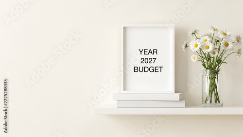 White mockup frame displaying financial budget text alongside fresh daisies inside glass vase standing upon books