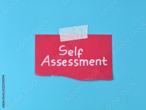 Top view of handwritten Self Assessment message on red torn paper attached with tape on blue background. Concept for personal development, evaluation, business strategy, and performance test