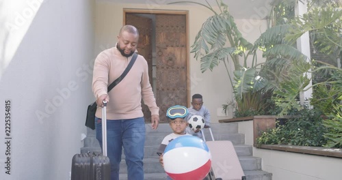 Phone pinging African American dad, two boys heading to car carrying balls, loading bags for trip