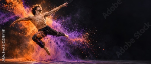 Male dancer leaping in explosion of orange and purple powder on black background with copyspace
