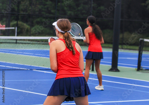 Female Tennis Players Prepare for a Doubles Match on a Blue Court