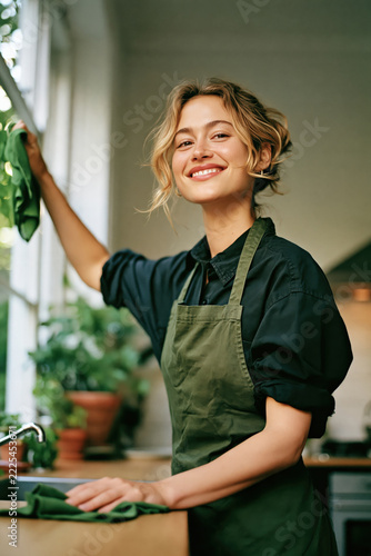 Smiling Woman Cleaning Kitchen Window with Green Cloth Created with Generative AI Technology AI Generative