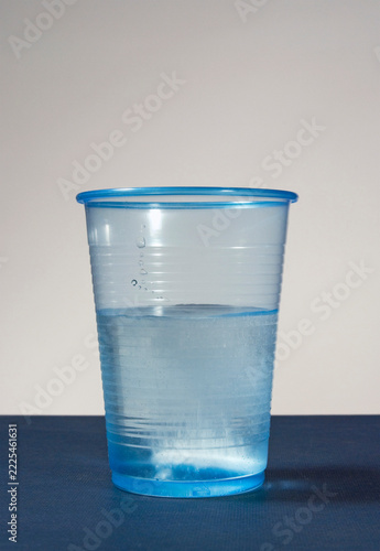 plastic cup of water with effervescent tablet inside