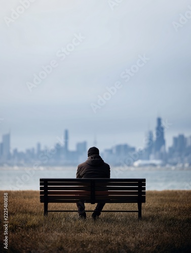 man sitting on bench overlooking city skyline