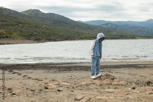 Child standing on rock at reservoir with low water level due