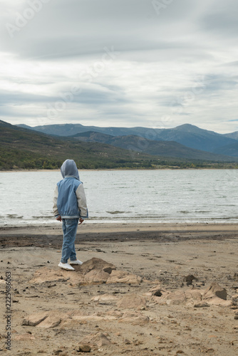 Child standing on dry shore of low water reservoir in drought