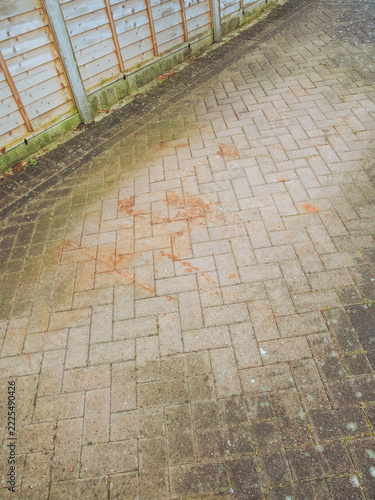 A dirty drive way in need of a clean with with rust marks from a skip, algae and lichen