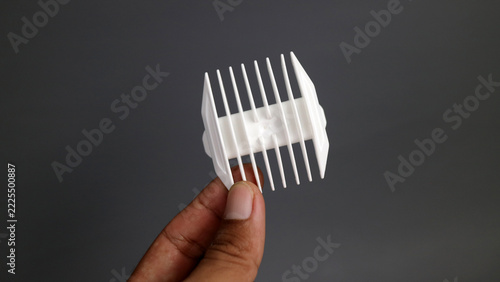 white plastic hair clipper comb attachment held by human hand