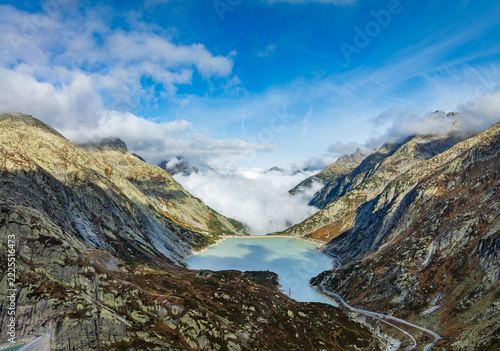 Drone photo of turquoise mountain lake Räterichsbodensee with low clouds and alpine fog in Swiss Alps