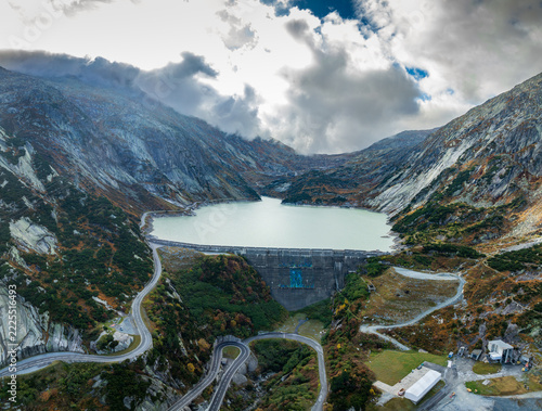Drone photo of turquoise mountain lake Räterichsbodensee with low clouds and alpine fog in Swiss Alps