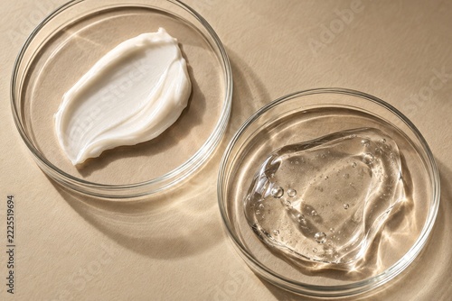 Clear petri dishes holding white cream and transparent gel on beige