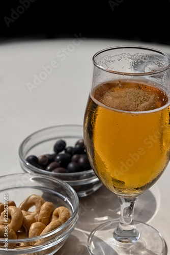 Obraz na plátně Glass of lager beer with olives and Taralli biscuit snacks on a table