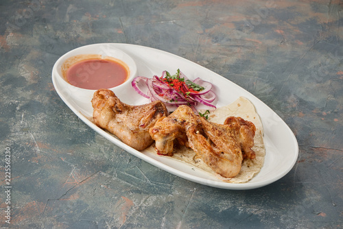 Grilled chicken wings served with dipping sauce and sliced onions