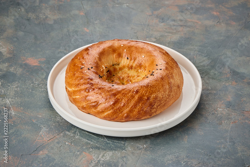 A freshly baked round bread with a golden crust on a white plate