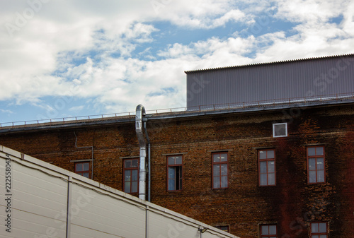 An old brick factory with windows against the horizon. A red-brick building against the horizon. An industrial brick building with windows in an industrial area.