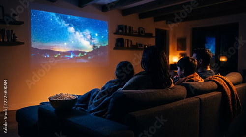 Family movie night seen from behind the sofa with projector light and popcorn, warm desaturated look