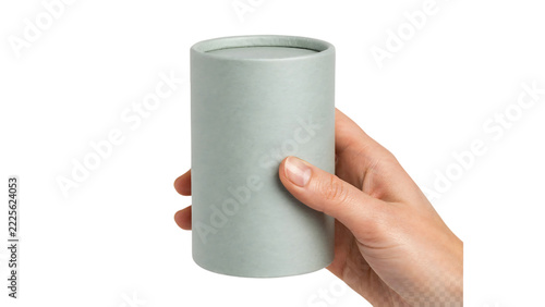 Hand holding a cylindrical cardboard container during a studio shoot with soft lighting and selective focus for product packaging concepts
