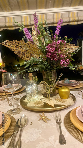 Luxury table place setting with golden dragonfly ornaments, floral arrangement and silverware