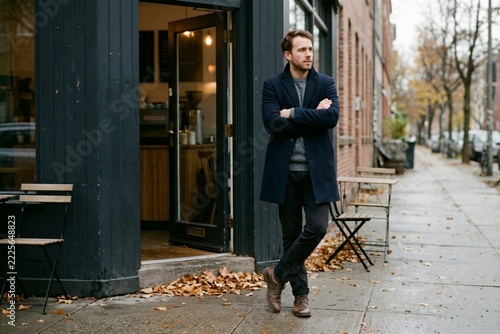 Pensive man standing outside a cafe on an autumn city street