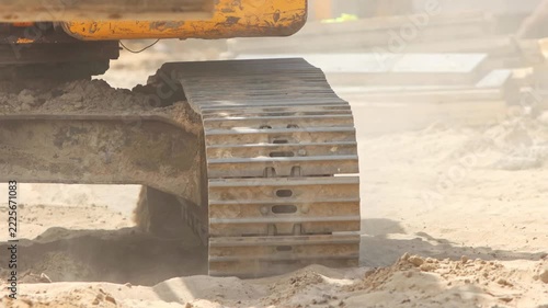 Excavator continuous tracks moving on sandy ground