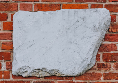 Blank White Marble Slab with Rough Natural Edges on a Red Brick Wall