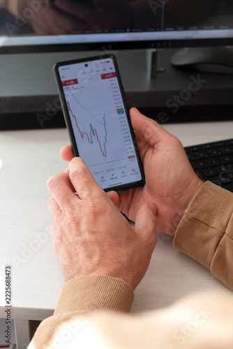 Close-Up of a Man’s Hands Using a Smart phone to Check Diagrams.