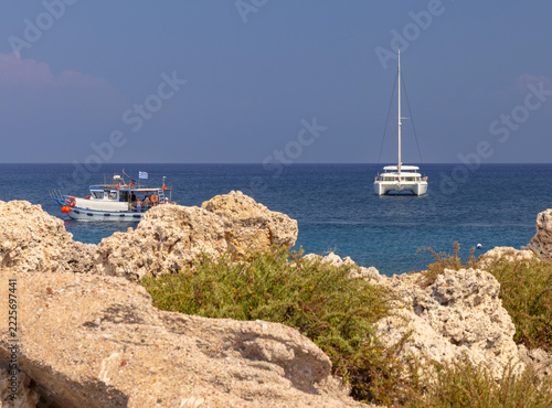 White Sailing Catamaran Near Rocky Coast of Rhodes, Greece