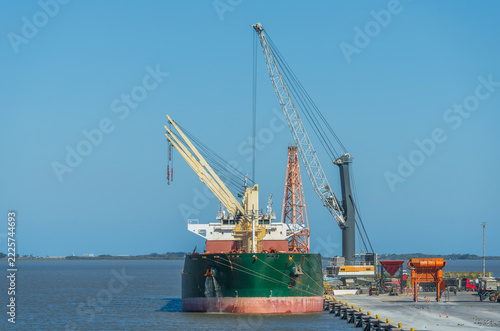 Large cargo ship berthed at a port terminal dock alongside high harbor cranes for unloading operations