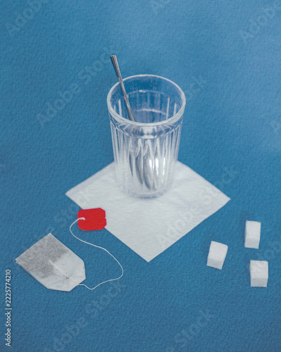 Glass Cup and Used Tea Bag on a Blue Textured Background