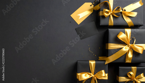 Black Friday gift boxes with gold ribbons tags and credit card on dark background