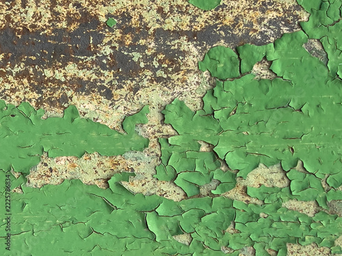 Close-up peeling green paint on rusty corroded metal surface showing cracked texture and flaking layers of aged coating and exposed substrate under weathered finish