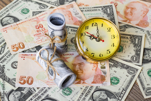 Arranged with rolled-up US dollars, a round yellow clock, and a fifty-Turkish-lira banknotes